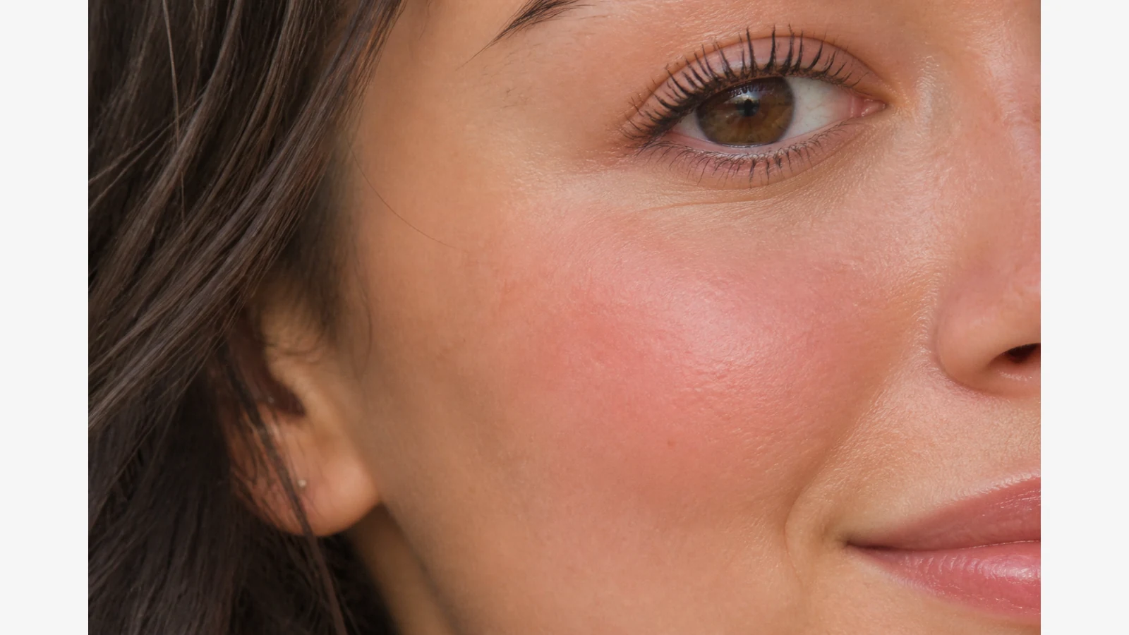 Natural-looking non-powdery blush flush on cheek in soft daylight